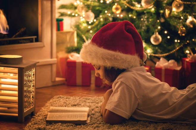 Jente leser bok under juletreet